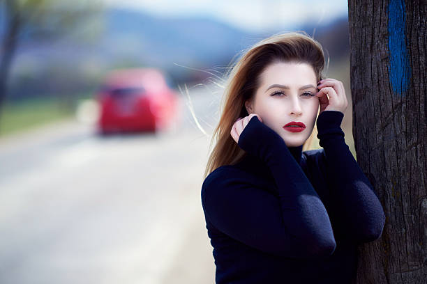 horizontal shot of attractive blond hair woman in black blouse feeling seductive and posing in the spring day, touching face, nostalgic attitude.