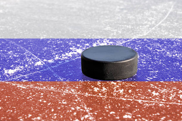 istock Black hockey puck on ice rink 528062460