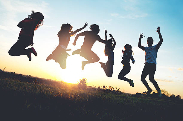 Group of people jumping outdoors; sunset stock photo