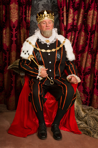 King in tudor costume sitting on his throne holding his scepter