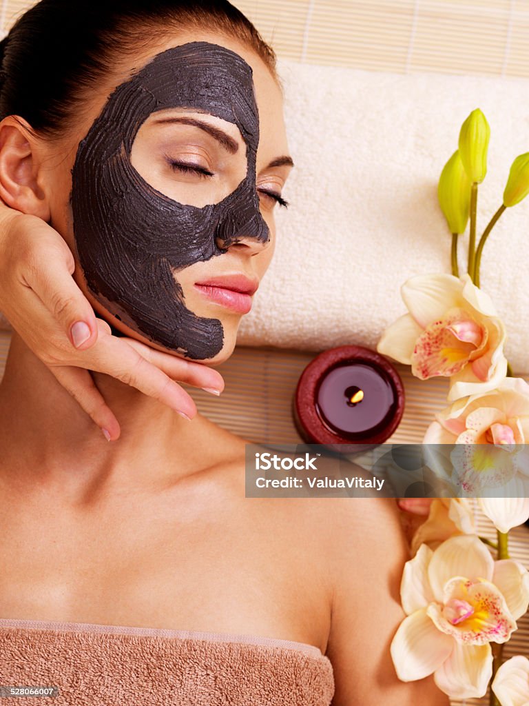 Cosmetologist doing massage on the woman's face  in sap salon Cosmetologist doing massage on the woman's face  in sap salon. Female with scrub cosmetic mask on face. Adult Stock Photo