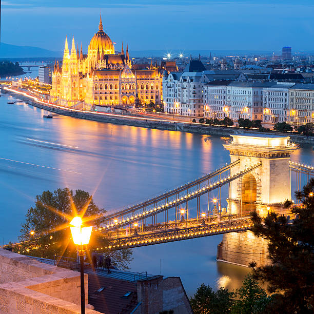 blick auf die kettenbrücke und das parlament in budapest in der dämmerung - chain bridge budapest night bridge stock-fotos und bilder