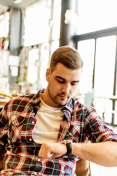 istock Handsome young man looking at wristwatch while enjoying coffee break 528067240