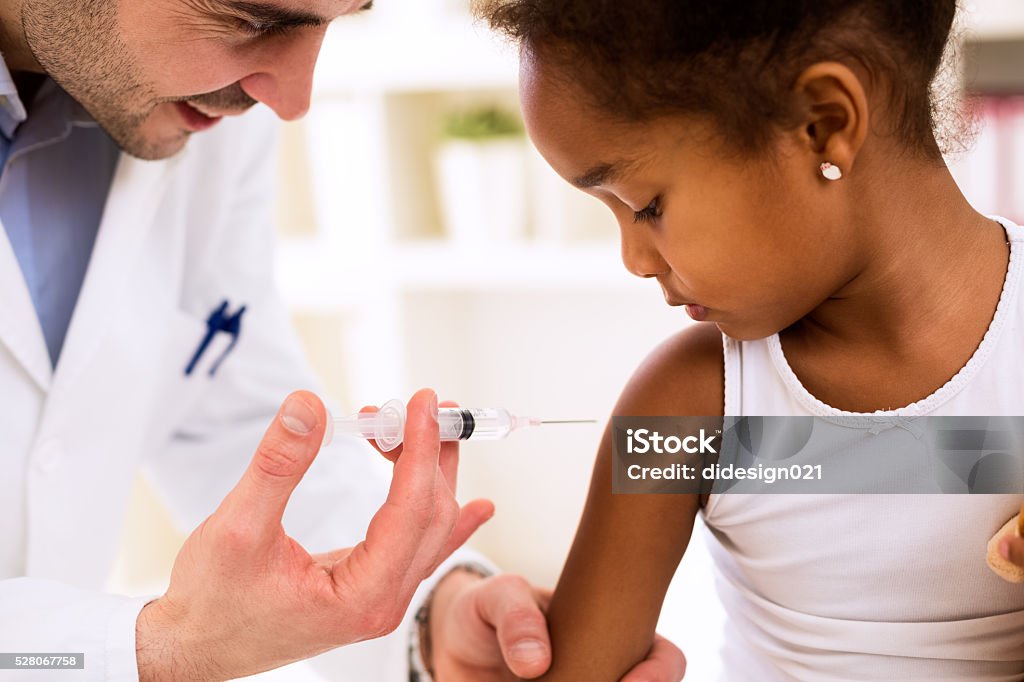 Doctor injecting vaccine to cute african girl Doctor pediatrician injecting vaccine to cute african girl Vaccination Stock Photo