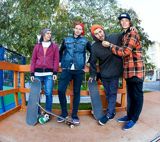 Four cheerful friend skateboarders in the skatepark