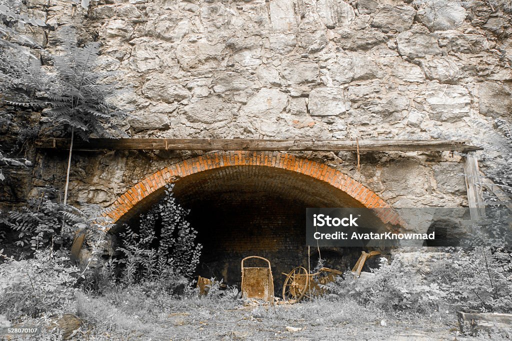 NY Mine Landscape in Kingston, New York. Horizontal image shows an old mine. Mine is in the side of a stone wall. A brick entrance leads into the mine and foliage surrounds the outside. Abandoned Stock Photo