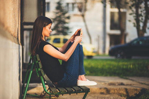 young woman sitting on bench with smart phone
