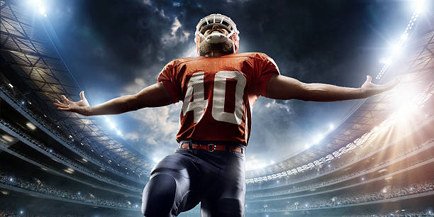 American football player is celebrating Professional American football player is celebrating his winning run. The player is on American football stadium full of spectators under an stormy evening sky. Player is wearing unbranded football cloths. football helmet and ball stock pictures, royalty-free photos & images