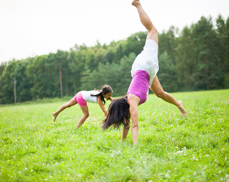 Mother and daughter cartwheeling in meadow
