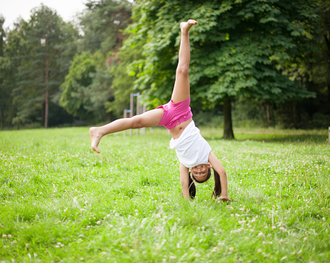 Little girl cartwheeling in meadow