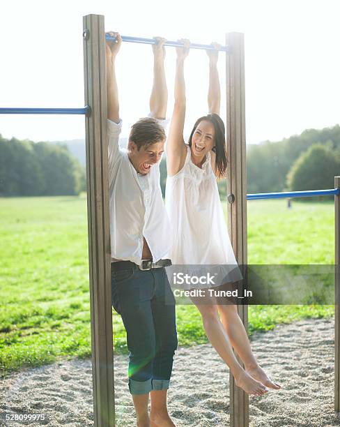 Young Couple Hanging On Bars At Playground Stock Photo - Download Image Now - Horizontal Bar, Hanging, Men