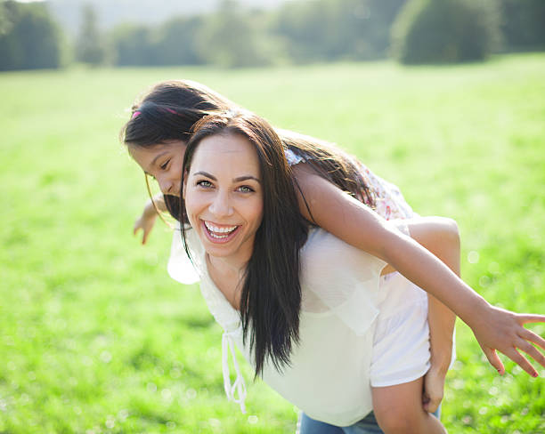 istock Mother carrying daughter piggyback, laughing 528100137