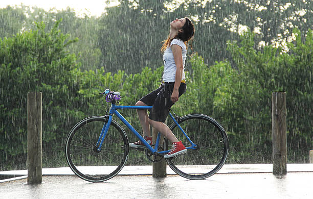 feeling rain young girl in the rain on a fixie bike red white blue bike stock pictures, royalty-free photos & images