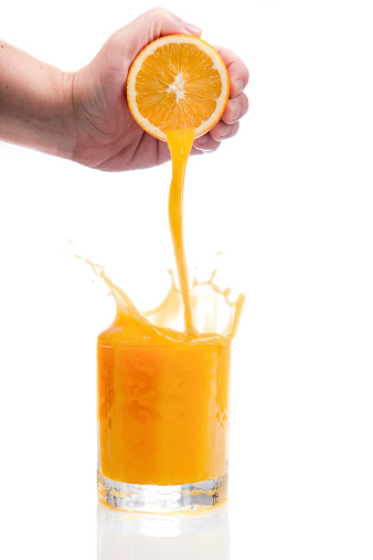 Hand squeezes fresh orange juice