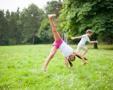 Brother and sister cartwheeling in meadow