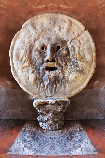 The Mouth of Truth (La Bocca della Verita) carved from Pavonazzo marble, in the portico of the church of Santa Maria in Cosmedin in Rome, Italy