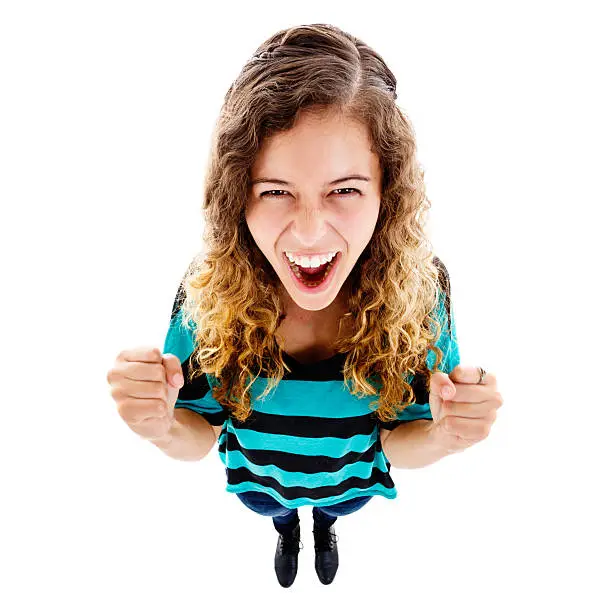 An exaggerated high-angle view of an excited young woman looking up, fists clenched and cheering. Isolated on white. Fish-eye lens exaggerates the perspective.