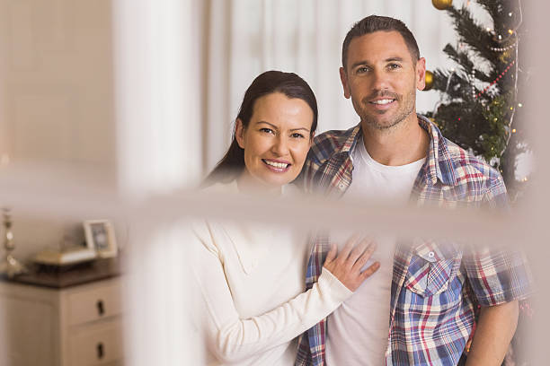 istock Smiling couple cuddling near the christmas tree 528104163