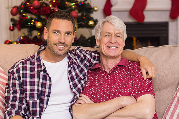 istock Father with arm around grandfather posing on sofa 528106879