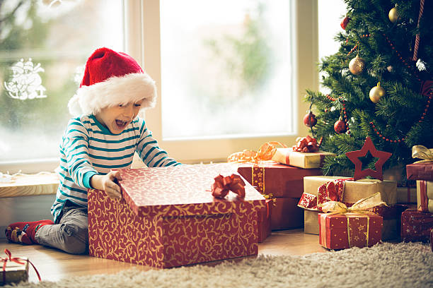 überrascht kleine junge öffnen weihnachtsgeschenk - opening present stock-fotos und bilder