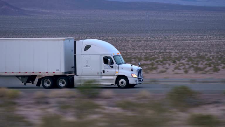 CLOSE UP: Freight semi truck driving and transporting goods on empty highway