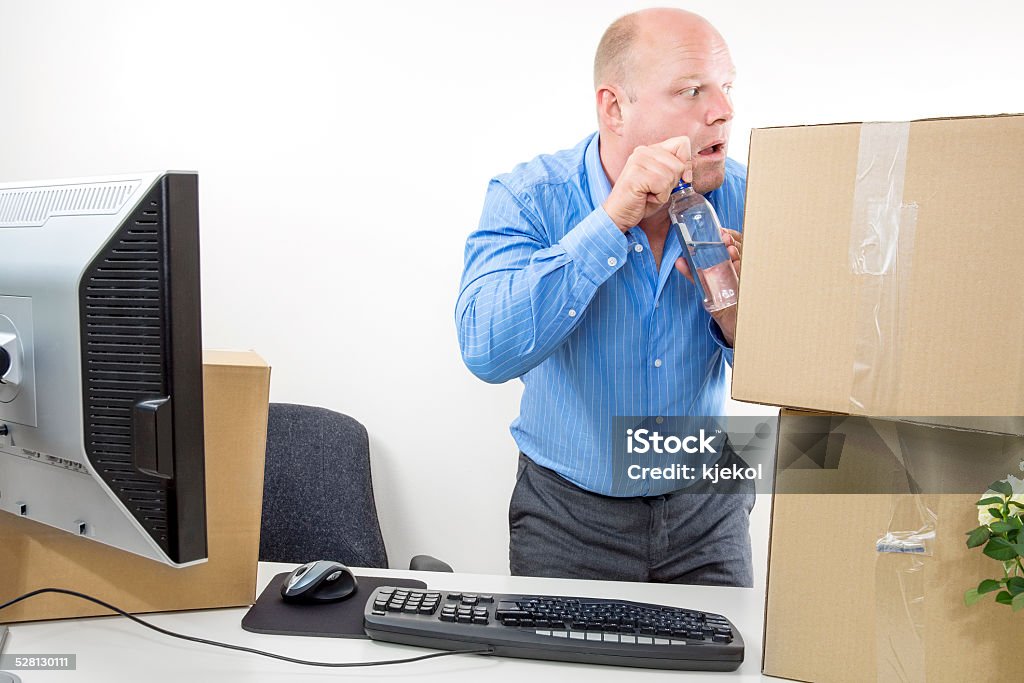 Businessman drinks alcohol at the office Office worker drinks vodka or hard liquor alcohol at his desk. Achievement Stock Photo