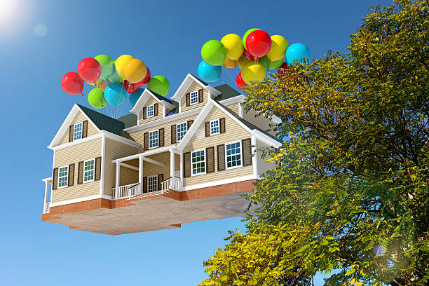 istock House flying in the sky with balloons, behind trees 528132099