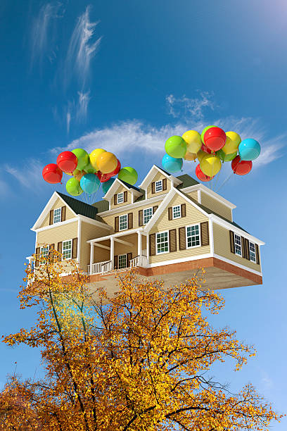 istock House flying in the sky with balloons, behind trees 528132115