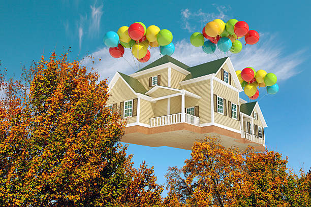 istock House flying in the sky with balloons, behind trees 528132117
