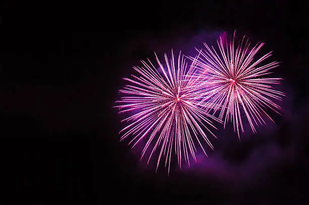 Pink fireworks on a dark background with space for copy on the left side