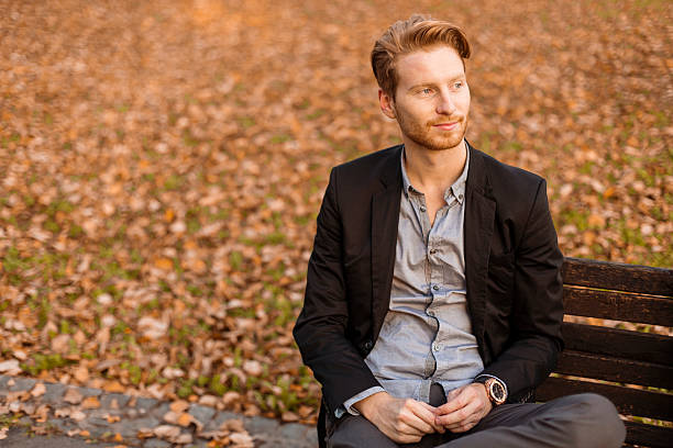 istock Young man at the bench in autumn park 528146473