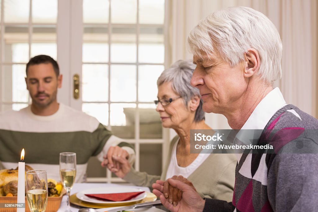 Family saying grace before christmas dinner Family saying grace before christmas dinner at home in the living room 30-39 Years Stock Photo