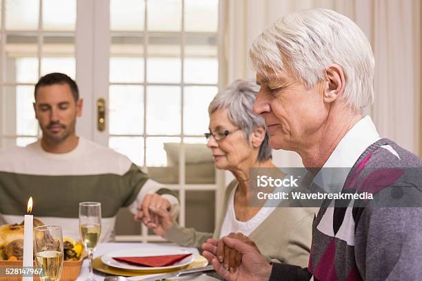 Family Saying Grace Before Christmas Dinner Stock Photo - Download Image Now - 30-39 Years, 35-39 Years, 60-64 Years