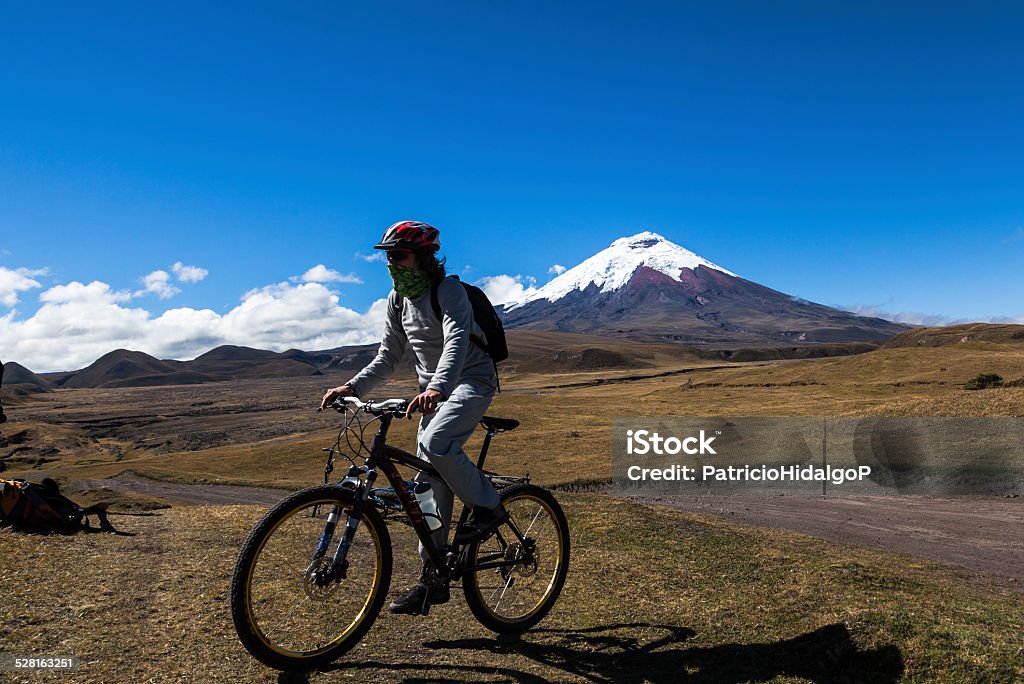 Cyclist and Cotopaxi volcano Cyclist in Cotopaxi National Park, about to start a morning walk along the slopes of the Cotopaxi volcano Bicycle Stock Photo