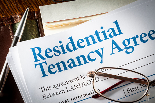 Residential Tenancy agreement with pen and glasses on desk