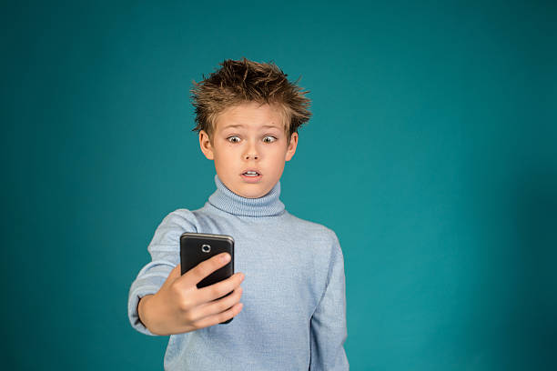 istock Surprised boy playing games on smartphone on blue background. 528183489