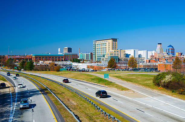Durham skyline and highway Durham city skyline with a highway in the foreground. durham north carolina stock pictures, royalty-free photos & images