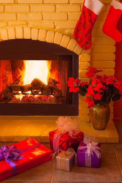 istock Christmas gifts sit next to burning brick Christmas fireplace (P 528194311