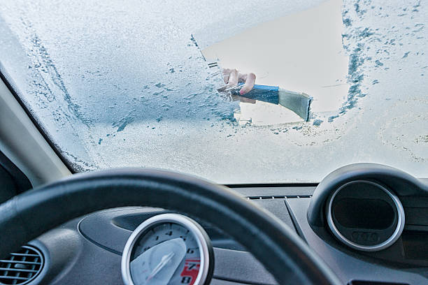 Woman scraping ice from car windscreen stock photo