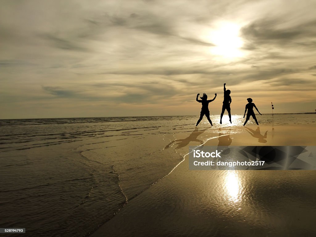 Young People Jumping On The Beach With Sunset Background Stock Photo -  Download Image Now - iStock