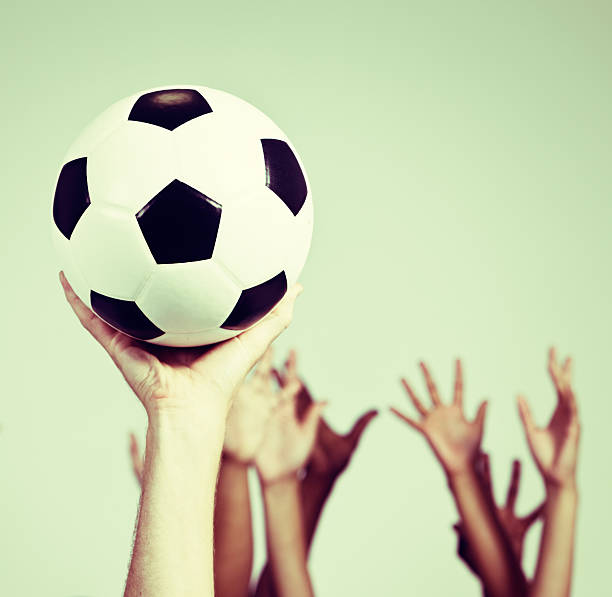 istock Multiple hands reach up, competng for a single soccer ball 528195761