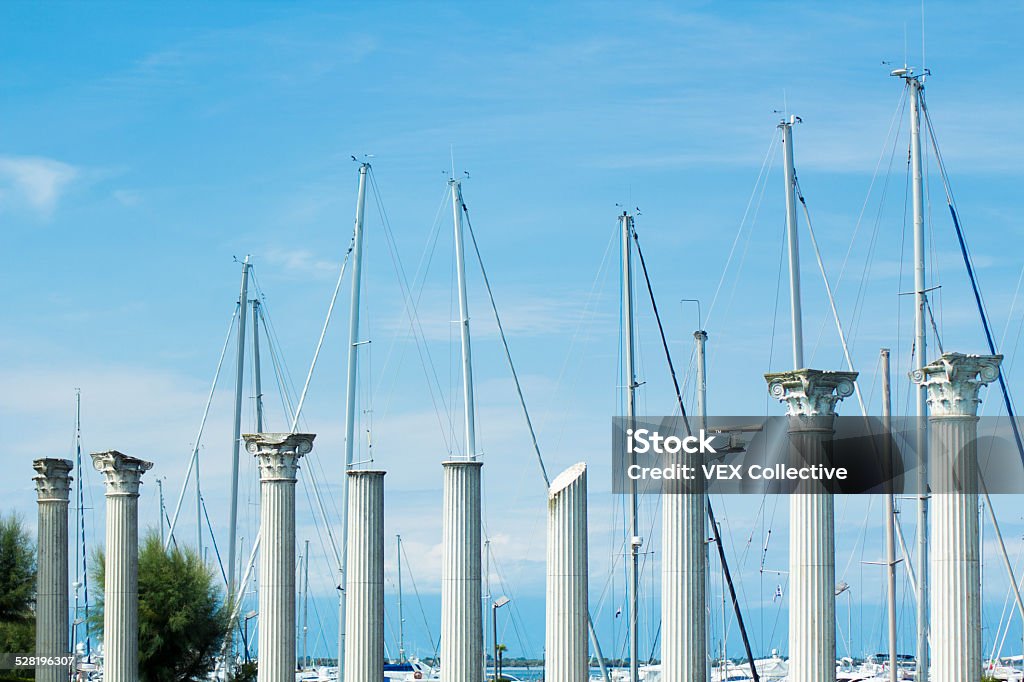 pillars lining this Italian marina The marina swimming pool is surrounded by old marble pillars and the harbour in the background. The picture was taken in Lignano, near Venice, Italy. Italian classic luxury.  Ancient Stock Photo