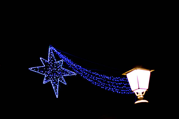 Illuminated neon Christmas star and old-fashioned lamp post against a black sky. Lots of copy space.