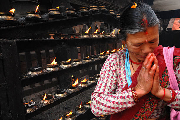 Kathmandu,Nepal-March 17,2014 : Nepalese female idol worship and sacred with Nepali lighting traditional butter-oil candles at a Hindu shrine on street in Kathmandu Durbar square on March 17,2014,Kathmandu city in Nepal.