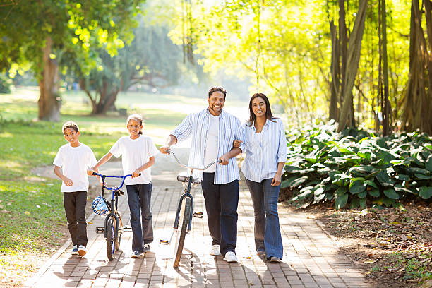 indian family walking outdoors happy indian family of four walking outdoors in the park indian man walking in park stock pictures, royalty-free photos & images