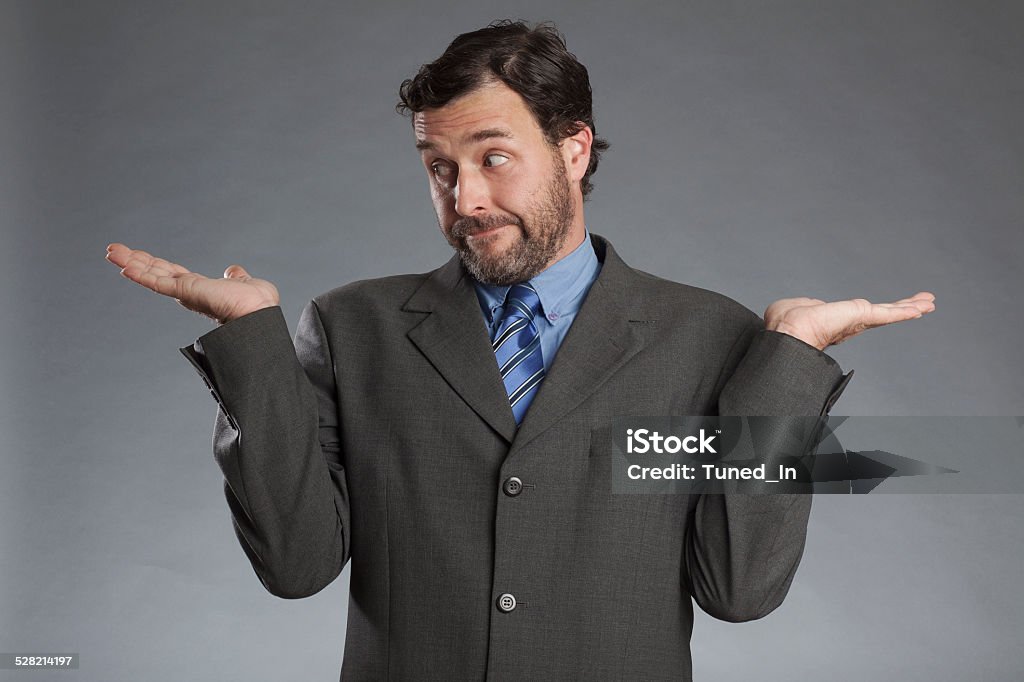 Skeptical businessman with both palms upwards against gray background Adult Stock Photo