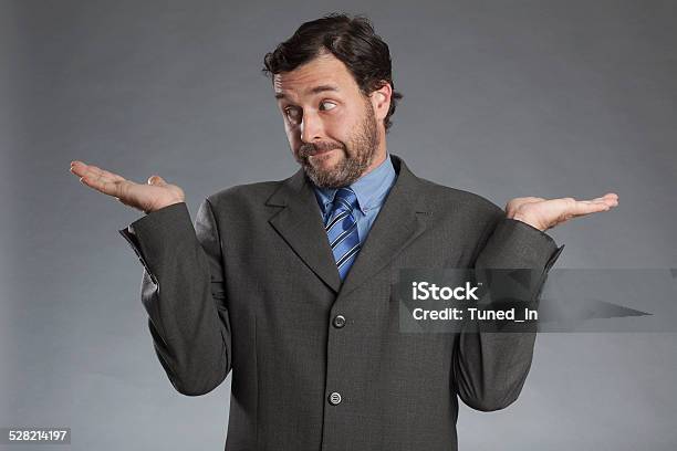 Skeptical Businessman With Both Palms Upwards Against Gray Background Stock Photo - Download Image Now