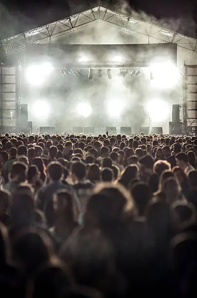 Photo of vertical scenario light white smoke people unrecognizable music festival