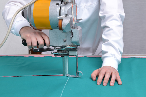 Taylor cutting fabric using a machine.Cutting fabric 