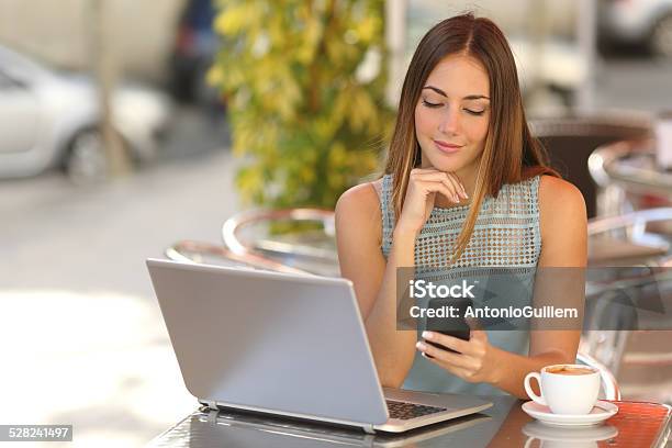 Mujer Trabajando Con Su Teléfono Y Computadora Portátil En Un Restaurante Foto de stock y más banco de imágenes de Hotel